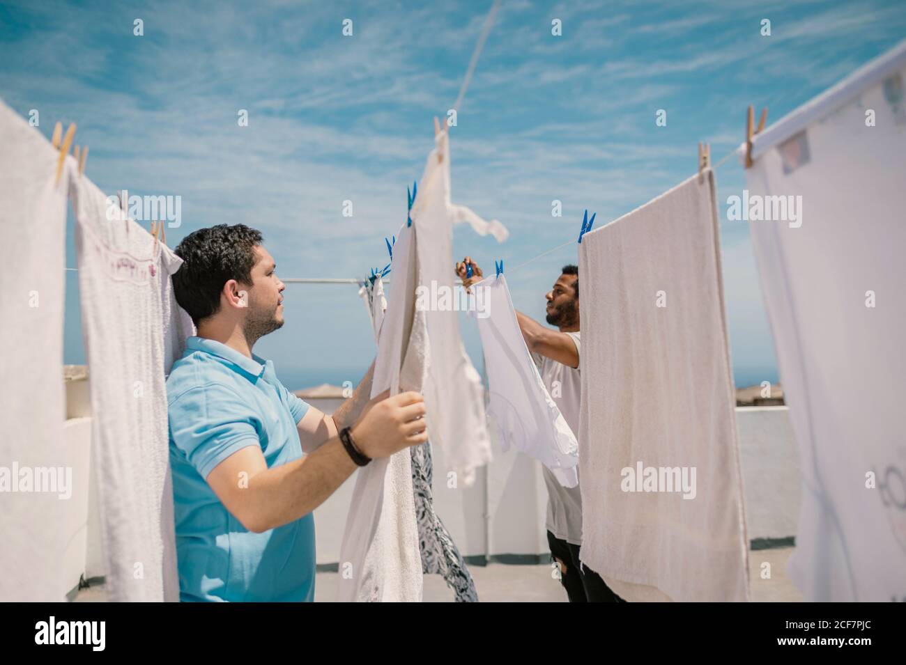 Multiracial men hanging clothes in bright day Stock Photo