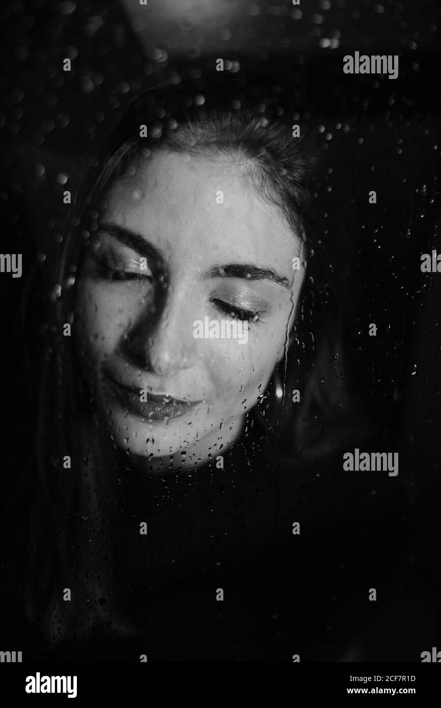Black And White Of Smiling Woman Standing Behind Glass In Water Drops