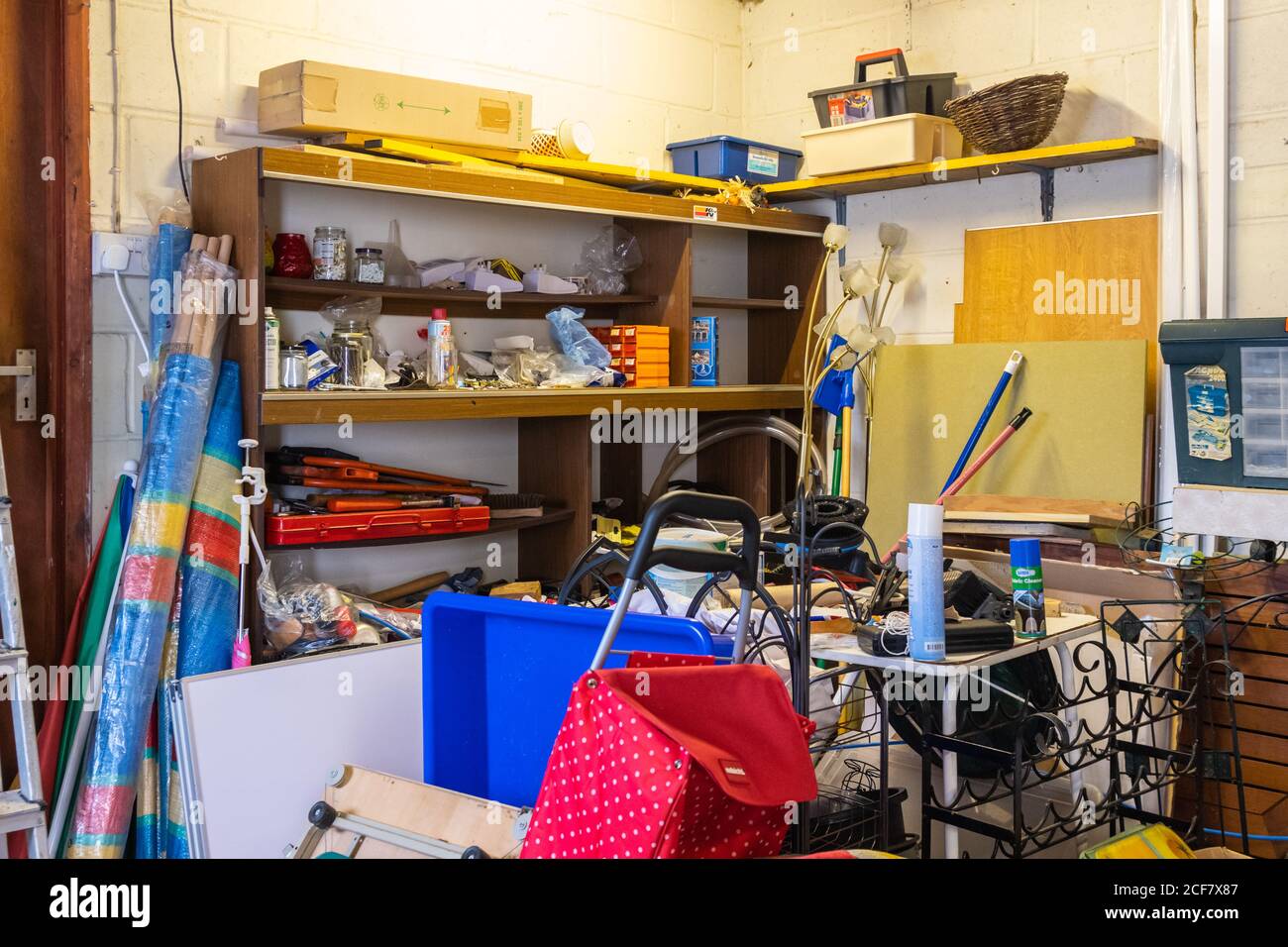 Cluttered storage space in a garage, full of untidy and messy junk from hoarding over several years. Clutter in garage. Stock Photo