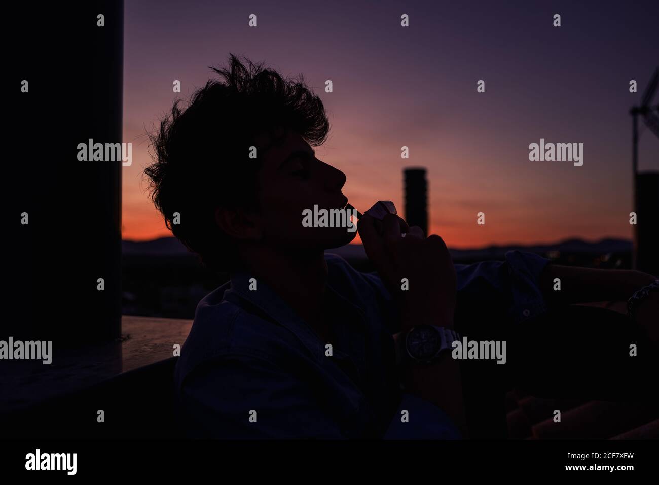 Young man smoking cigarette during sunset Stock Photo Alamy