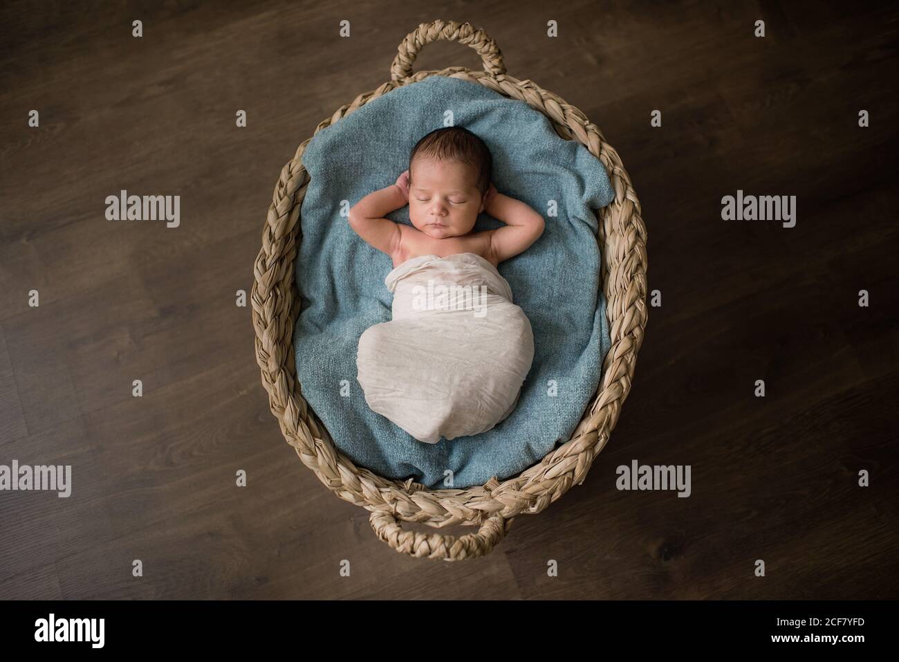 Top view of newborn baby wrapped in cloth lying on soft blanket and