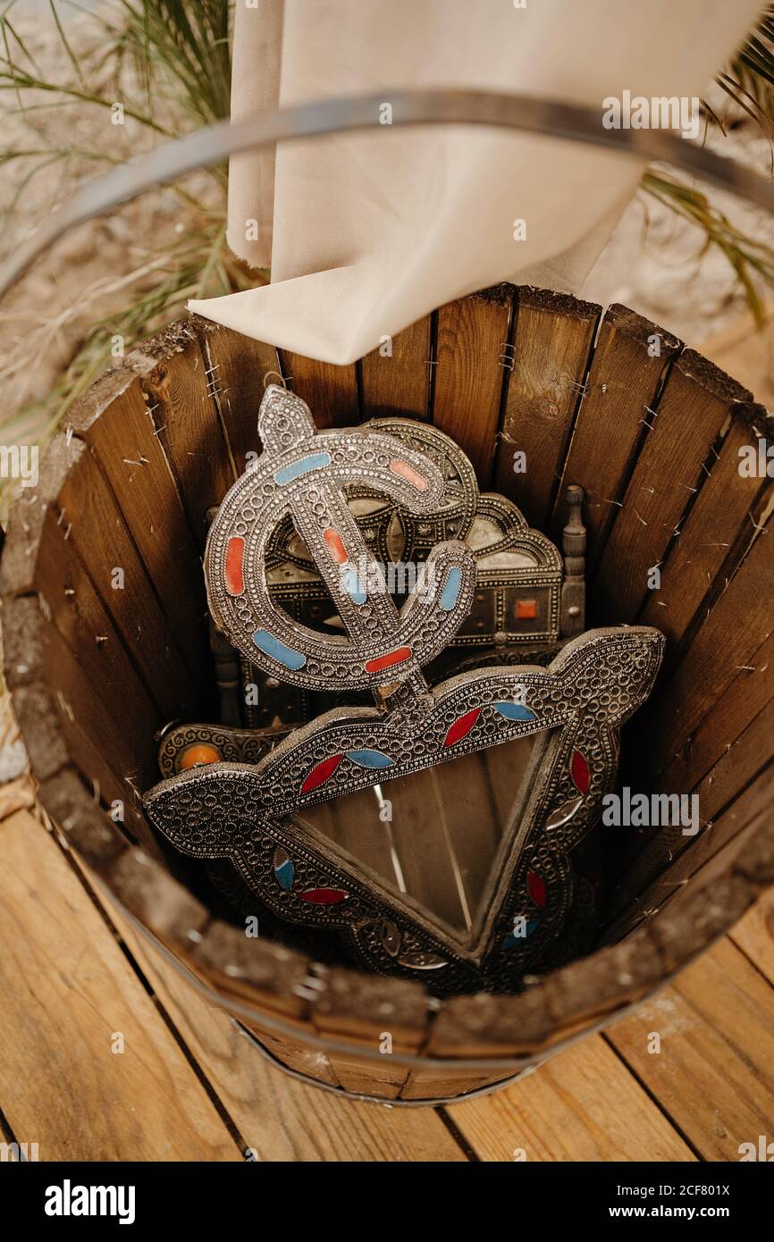 From above of authentic Moroccan metal souvenir with traditional pattern placed on wooden bucket Stock Photo