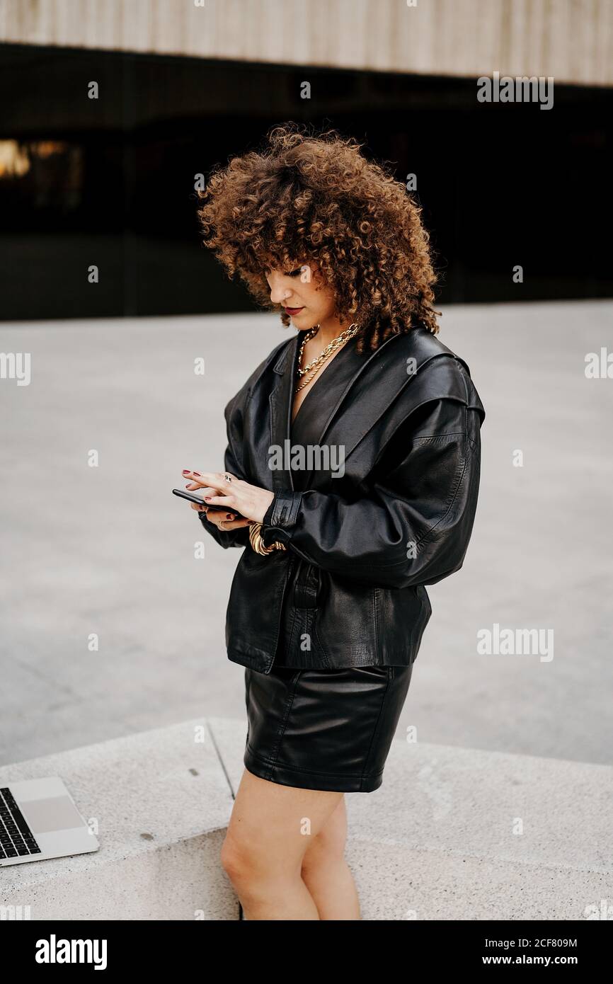 Side view of smart lady in vintage outfit browsing smartphone and ...