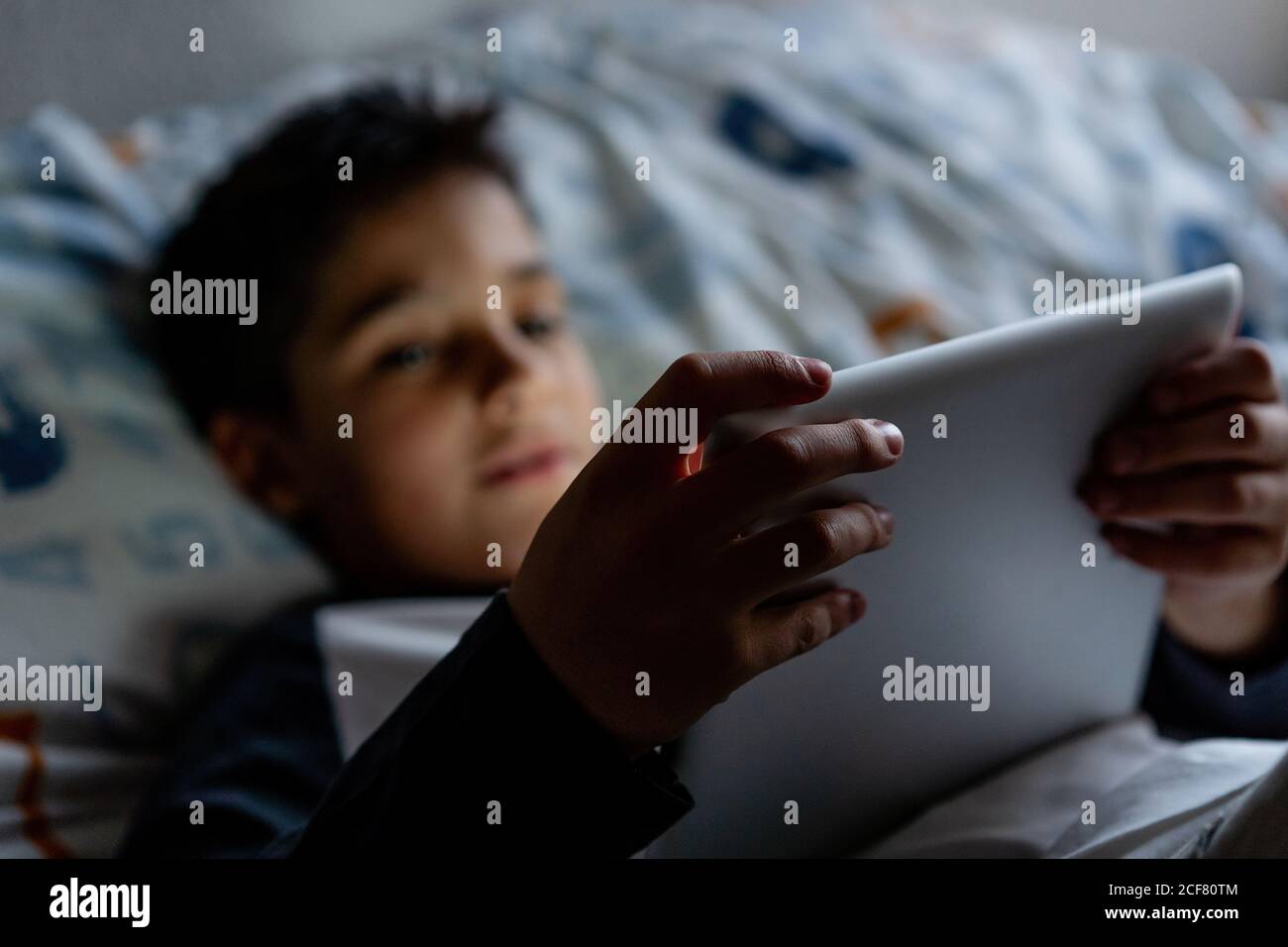 Delighted boy using tablet in bedroom during weekend Stock Photo