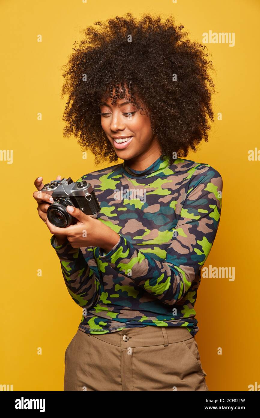 Professional cheerful female photographer with Afro hairstyle reviewing