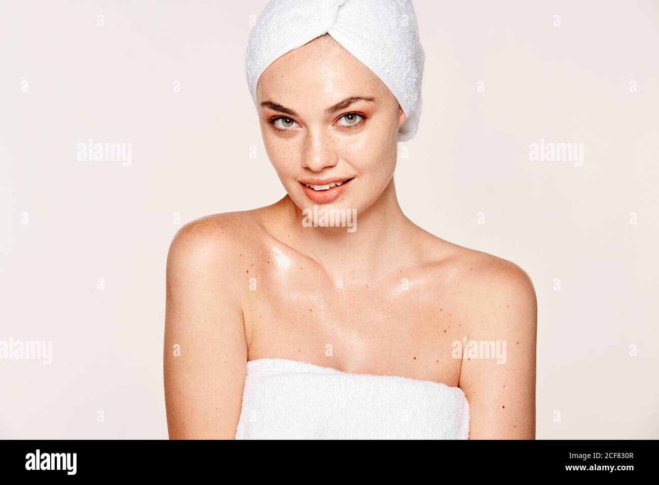 Goodlooking Woman with moisturized skin posing in towel on face and