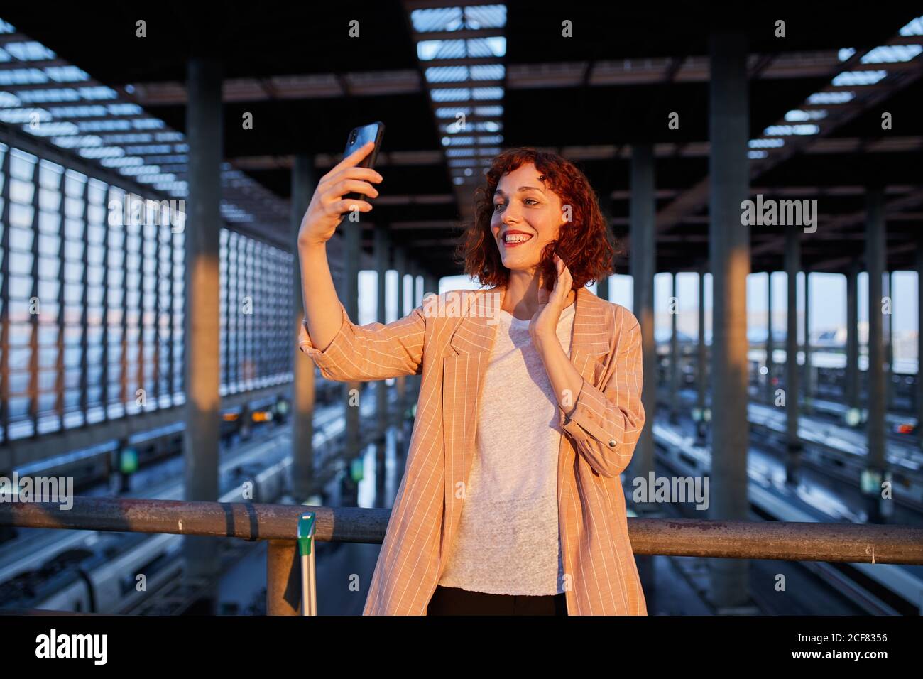 Smiling young Woman taking selfie at station Stock Photo