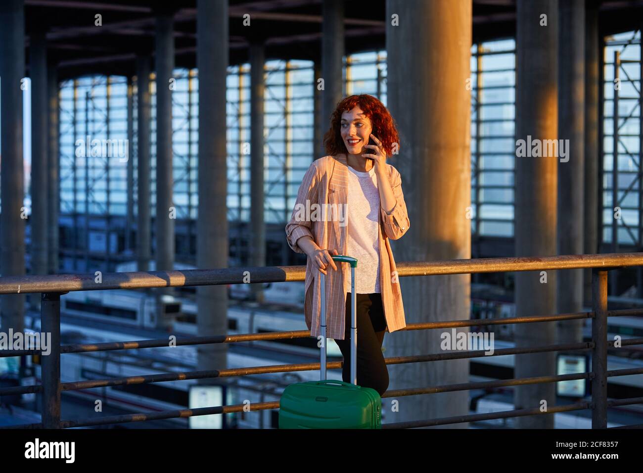 Smiling young Woman talking on phone at station Stock Photo