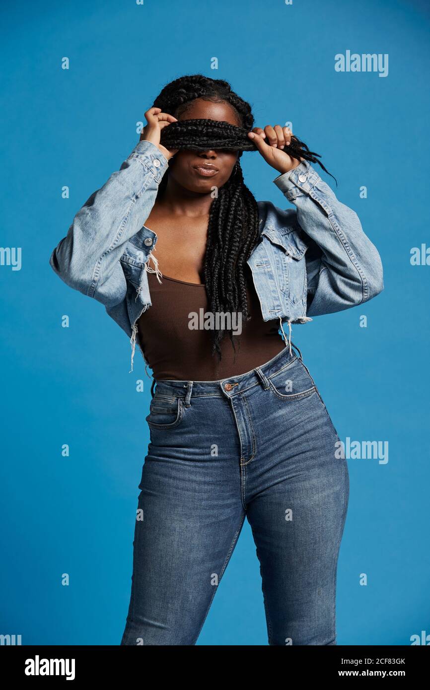 Chubby African American female in casual clothes pouting lips and covering eyes with braids against blue background Stock Photo Alamy
