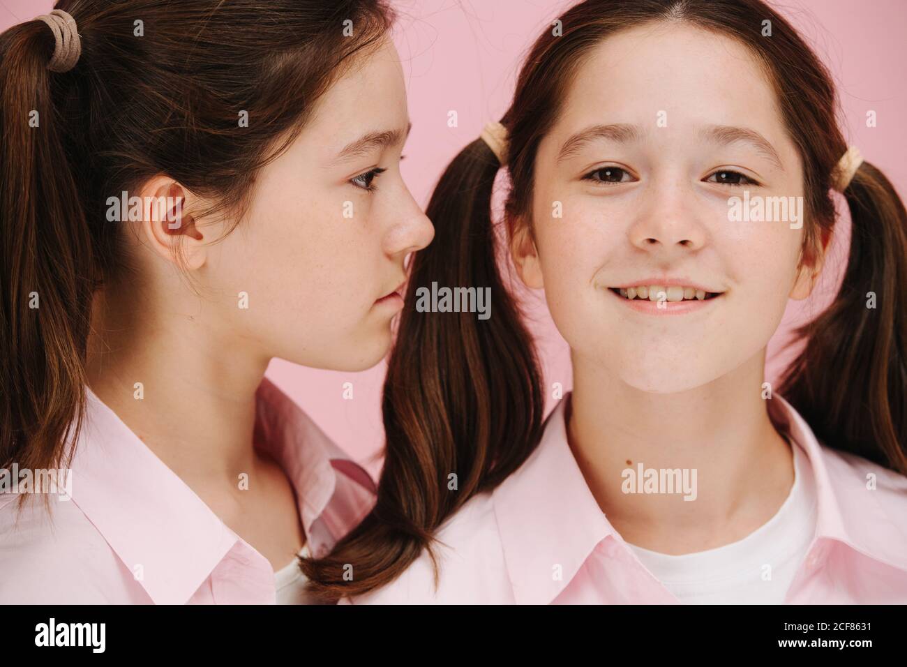 Beautiful little twin sisters posing. One is facing side other facing forward. Stock Photo