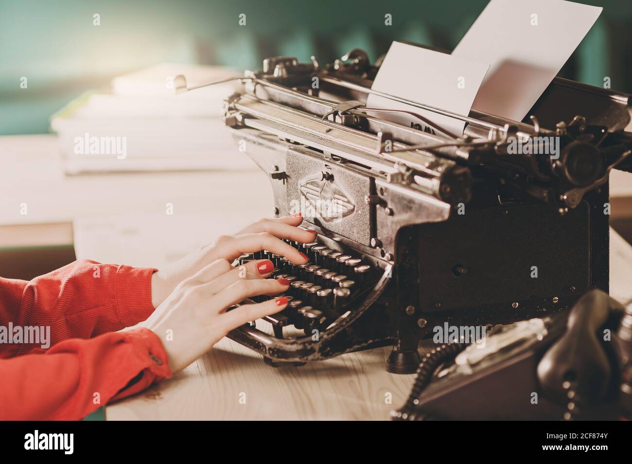 Secretary at old typewriter with telephone. Young woman using