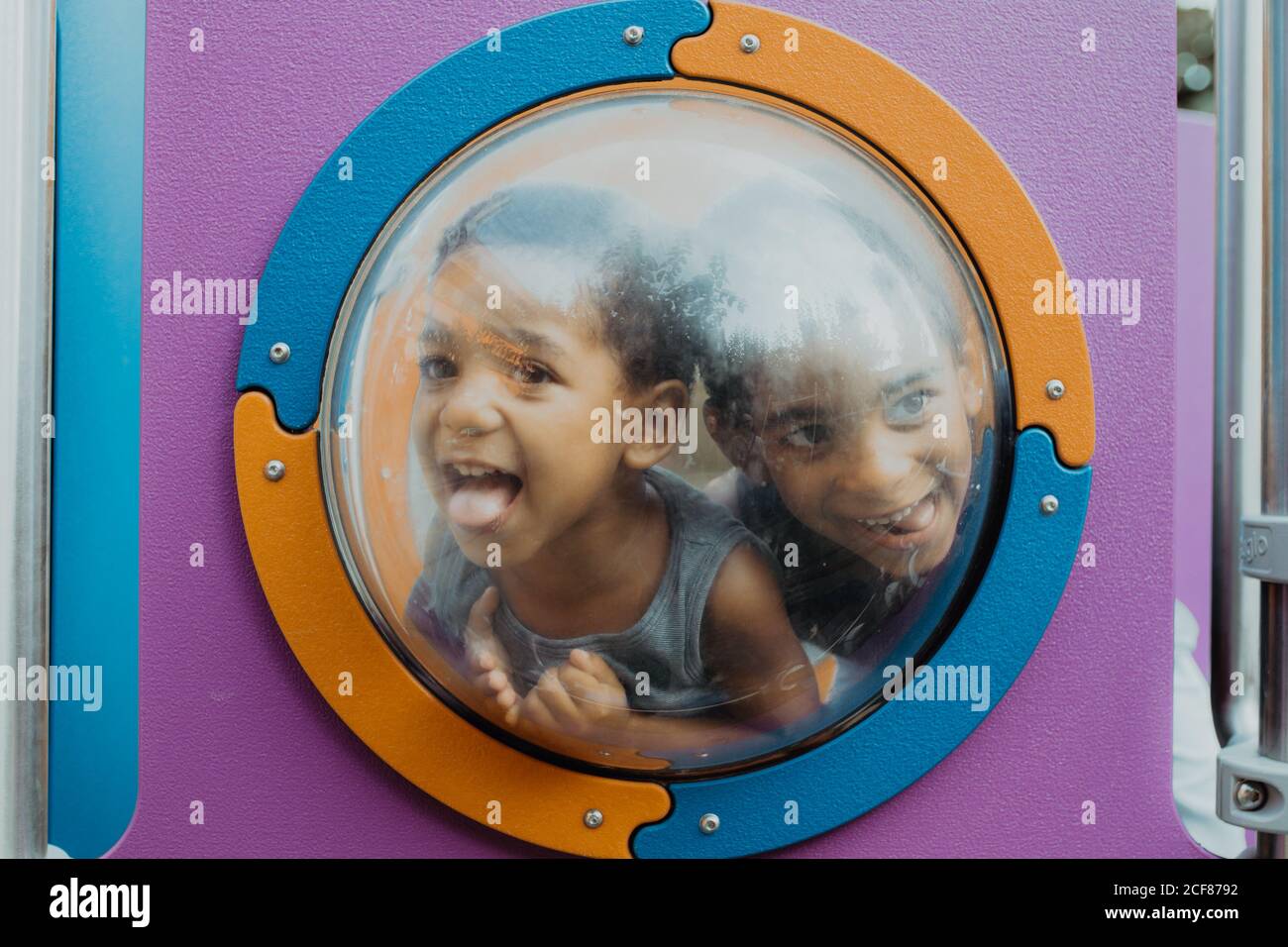 Two little African American boys looking away through porthole and
