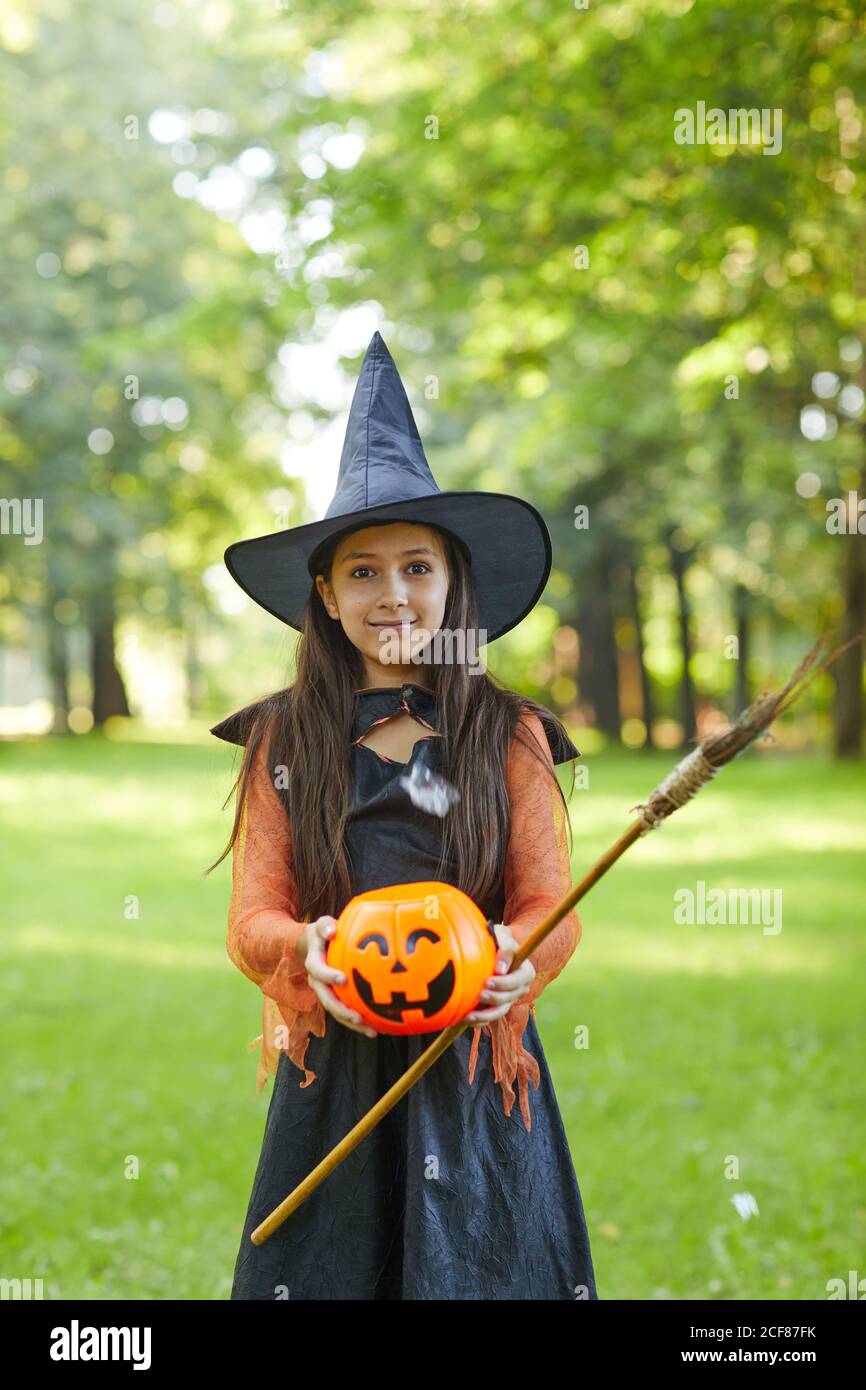 Portrait of little girl in witch costume looking at camera while standing in the park outdoors Stock Photo