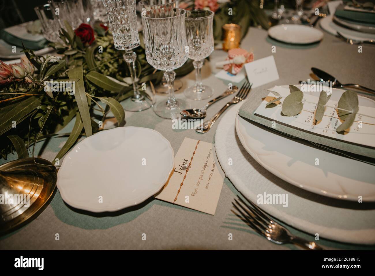 Various dishware and name card arranged with flowers and elegant glassware on table for wedding reception Stock Photo