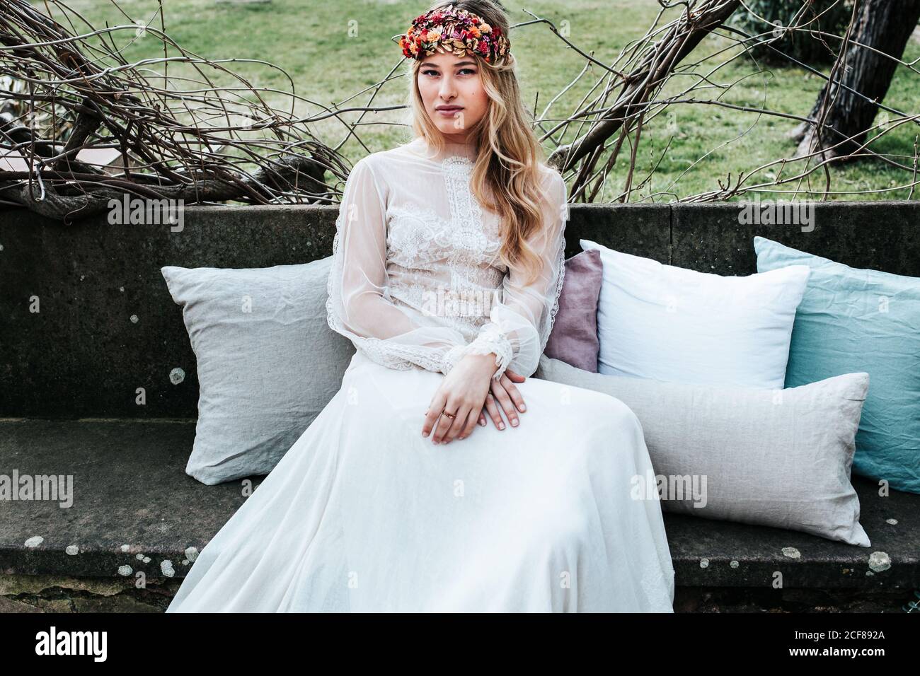 Young bride sitting on bench in garden Stock Photo