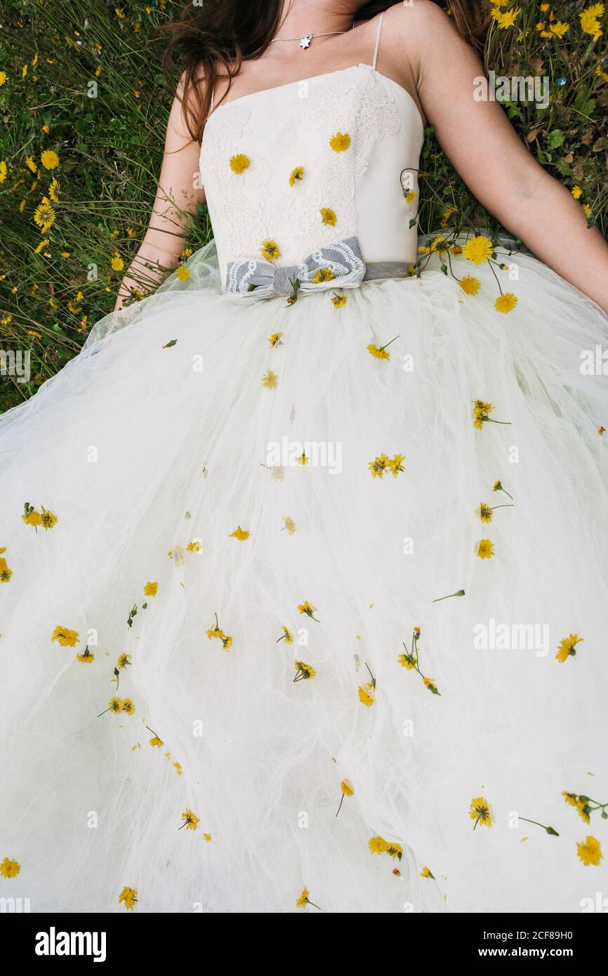 From above of newlywed female wearing white wedding dress and high heels  sitting with crossed legs in blooming field with yellow flowers Stock Photo  - Alamy
