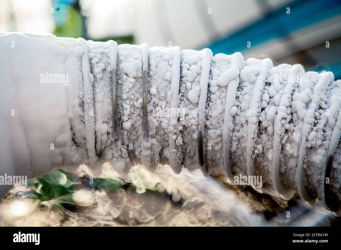 Closeup view of cooling pipe transferring liquid nitrogen surrounded by clouds of vapor on plant Stock Photo