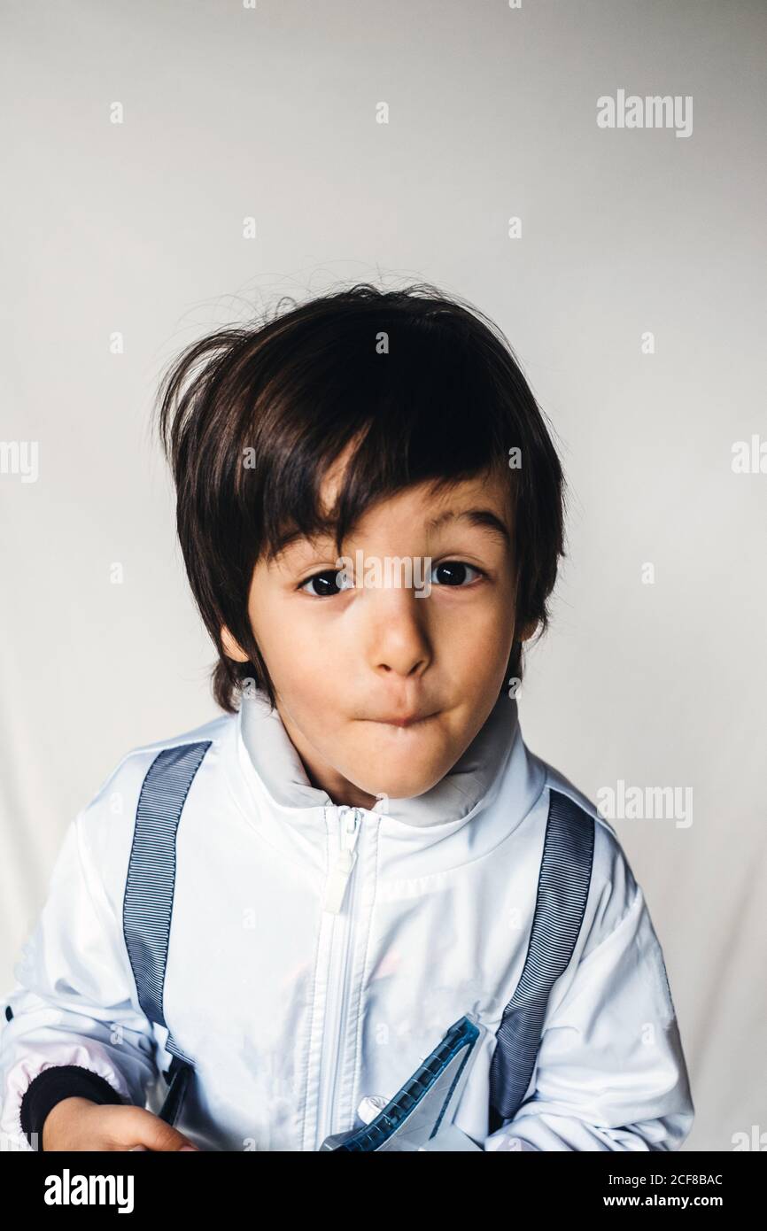 Positive child wearing spaceman uniform standing with toy spaceship looking at camera Stock Photo