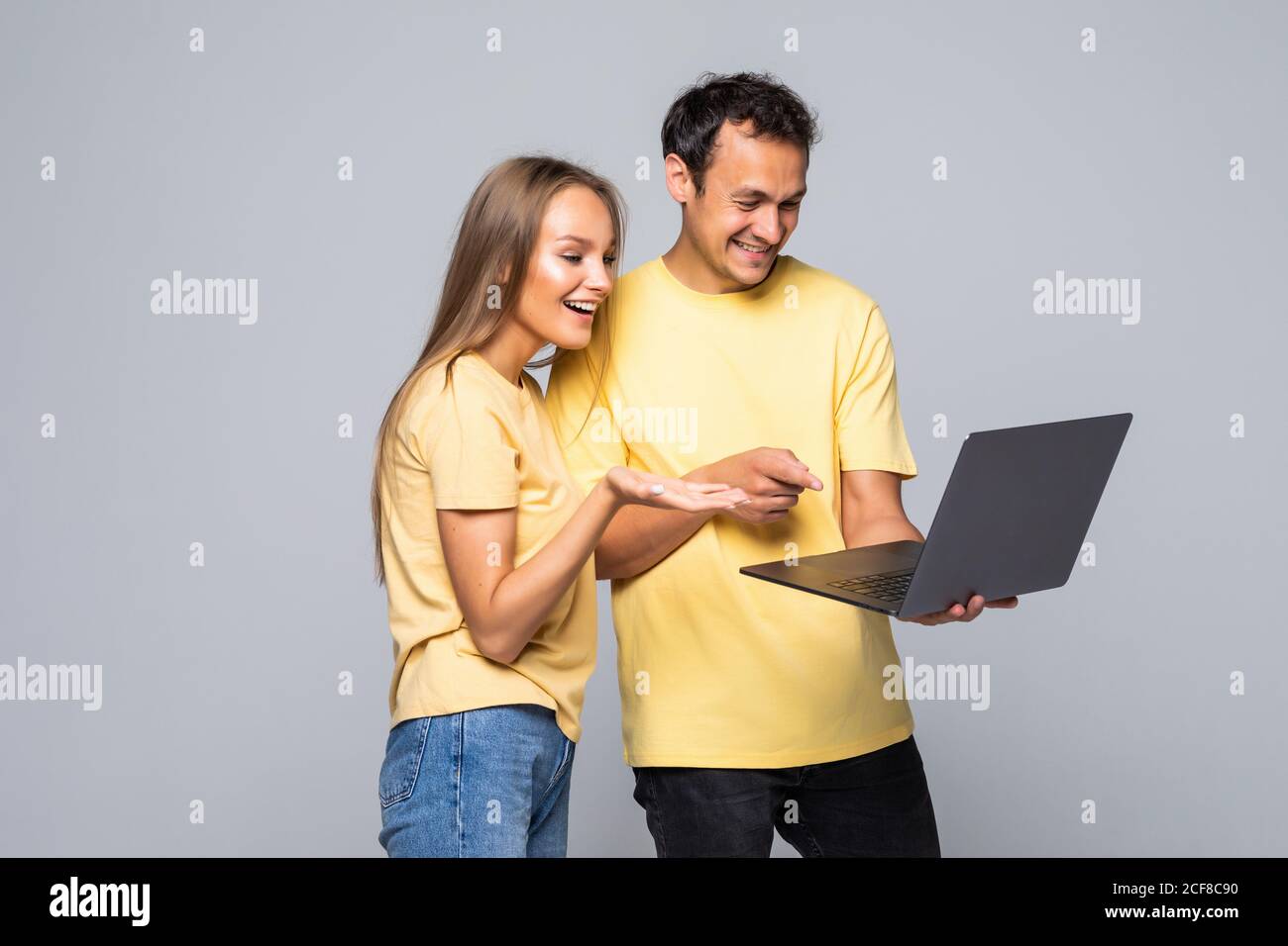 Portrait of a happy young couple using laptop computer while standing ...