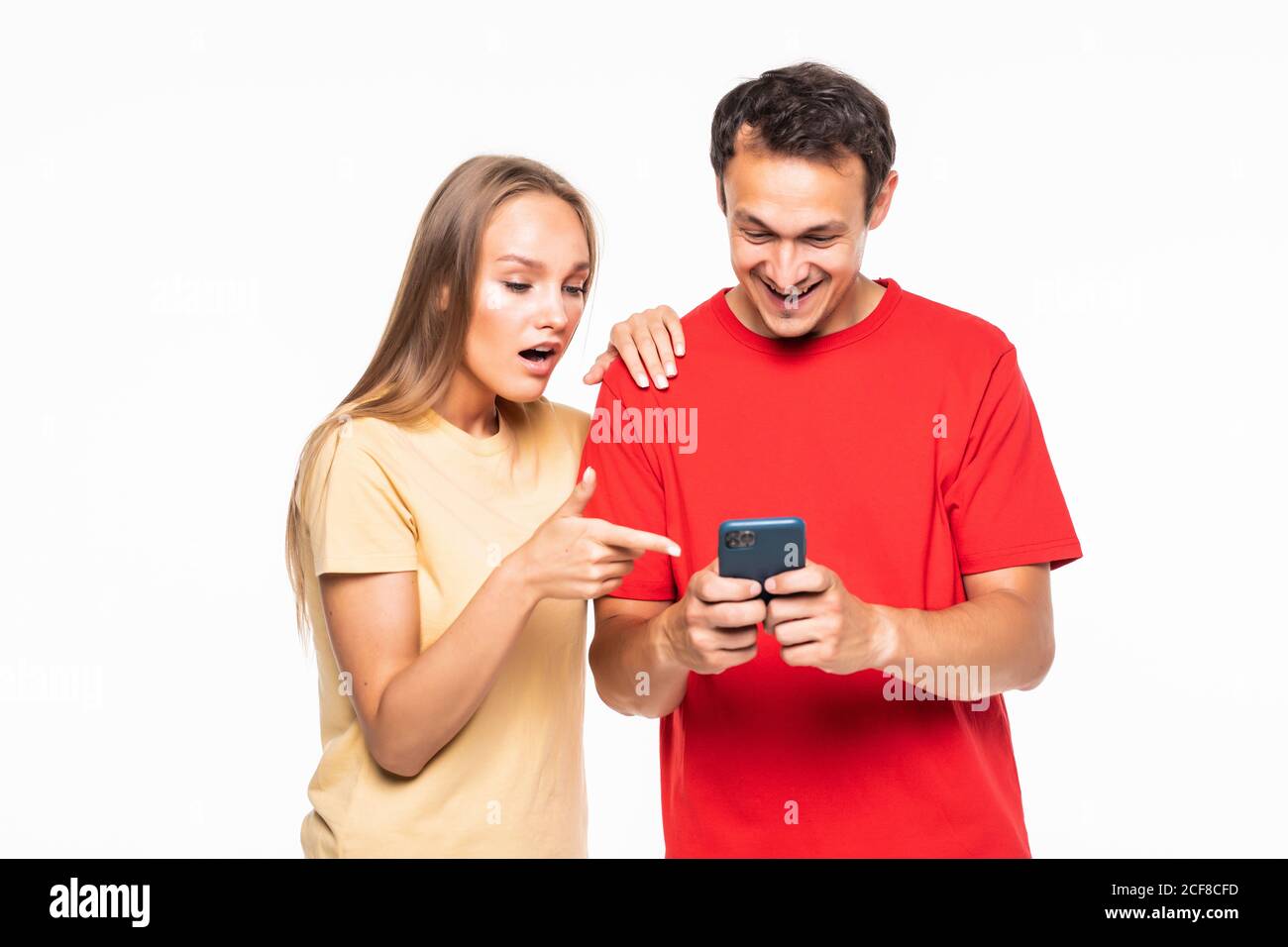 Young man and surprised woman are watching on the phone on white ...