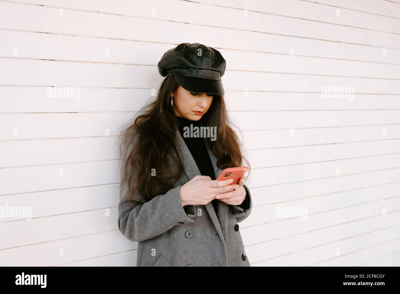 Woman using smartphone near wall Stock Photo
