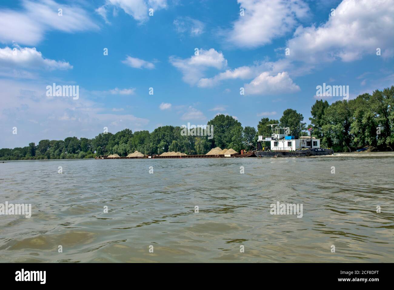 Novi Becej, Tisa River, Serbia, May 14, 2017. A large and powerful river boat pushes barges loaded with sand and gravel along the river. The ship sail Stock Photo