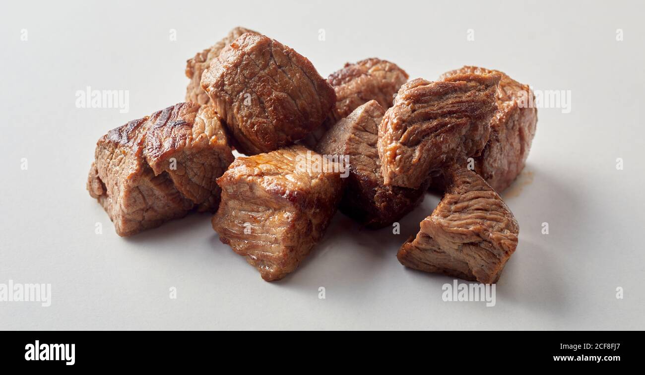 Cubed braised lean beef or venison for a goulash or ragout on a white background in close up Stock Photo