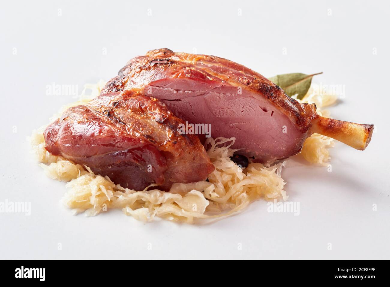 Sliced ham or pork hock on a bed of sauerkraut for traditional German cuisine over a white background Stock Photo