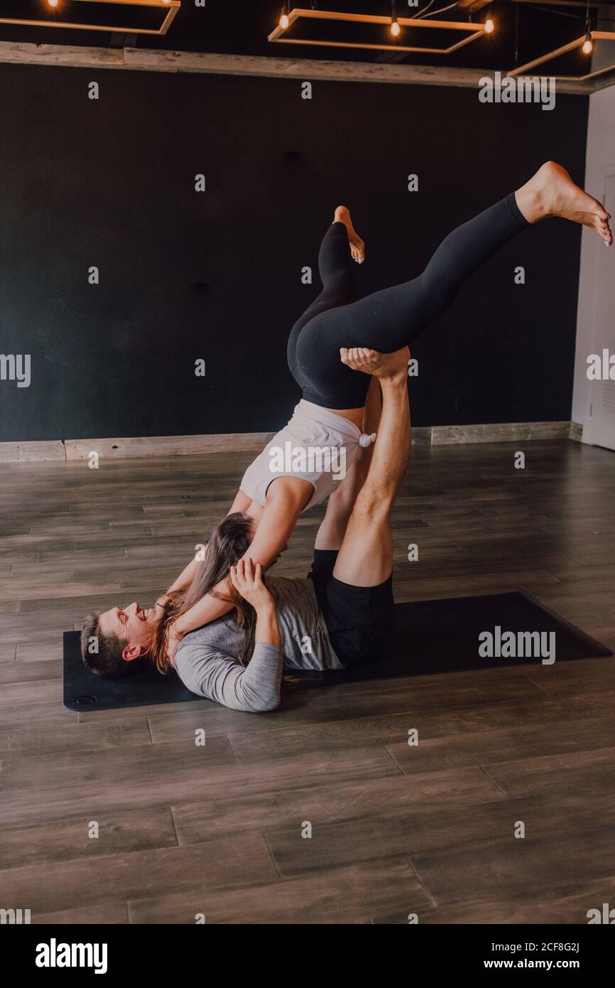 Side view of joyful athletic man with young female partner practicing