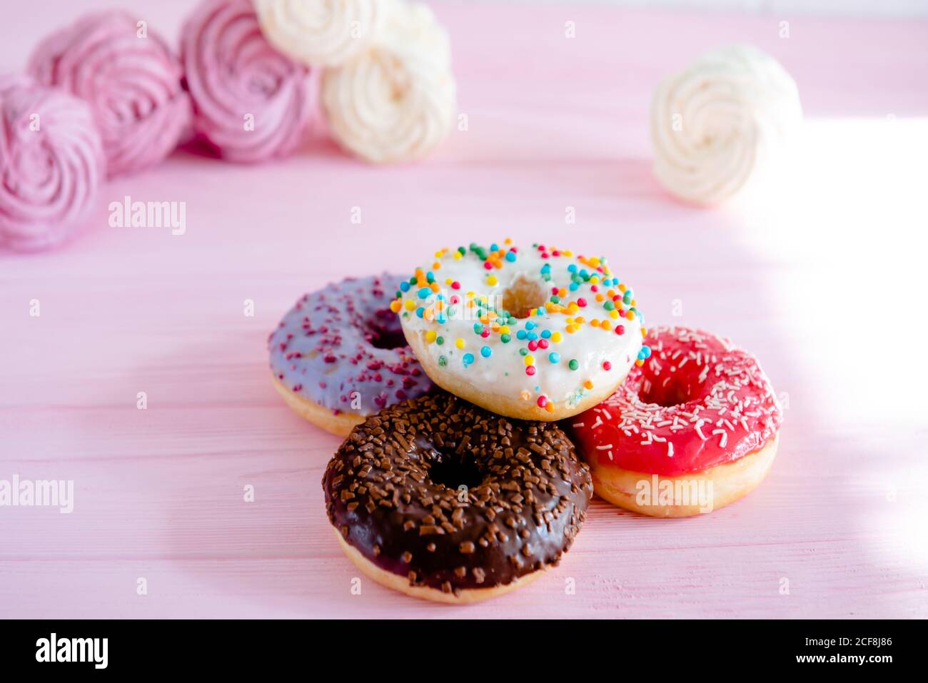 Variety of doughnuts and marshmallow on pink background. Junk food