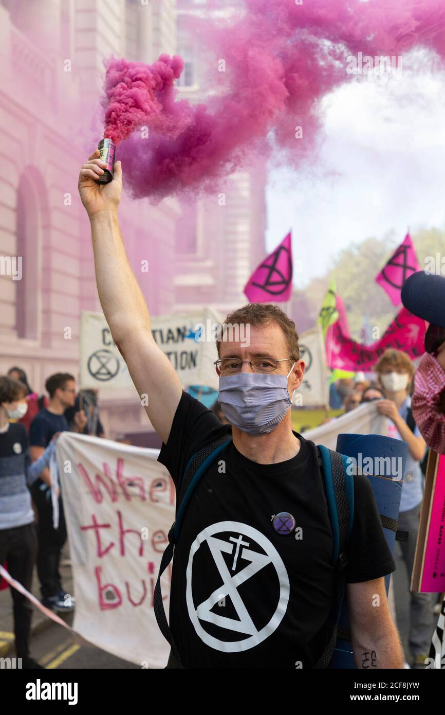 A protester holds up a pink coloured smoke bomb during Extinction Rebellion demonstration, London, 1 September 2020 Stock Photo