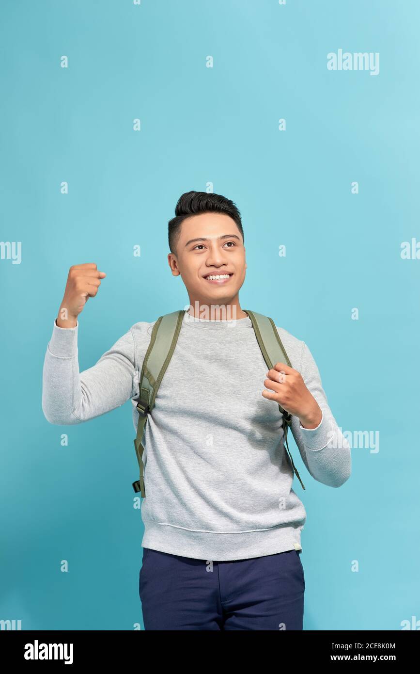 Handsome guy is celebrating a prize with raised hands over blue background Stock Photo