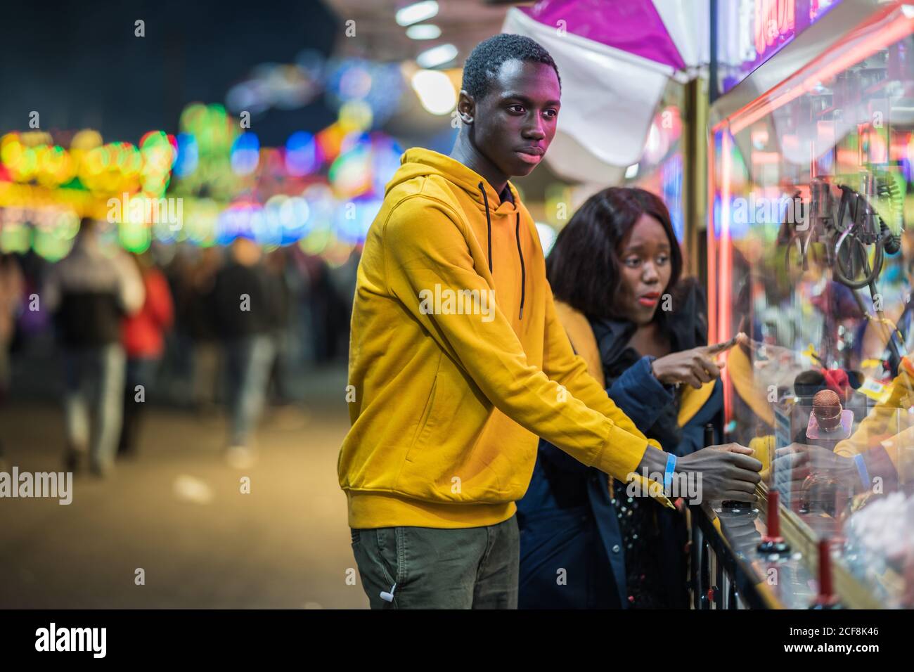 Black man playing claw crane for girlfriend Stock Photo