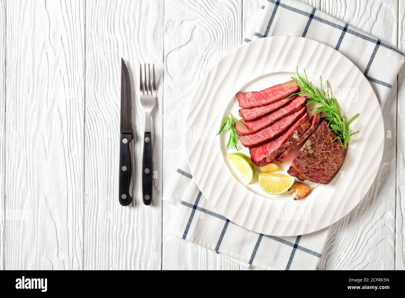 Cooked beef striploin steak panfried and sliced, served on a white