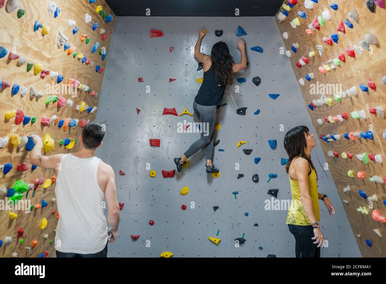Side view of male and female professional climbers in active wear hanging on wall and reading fir climbing in modern gym Stock Photo