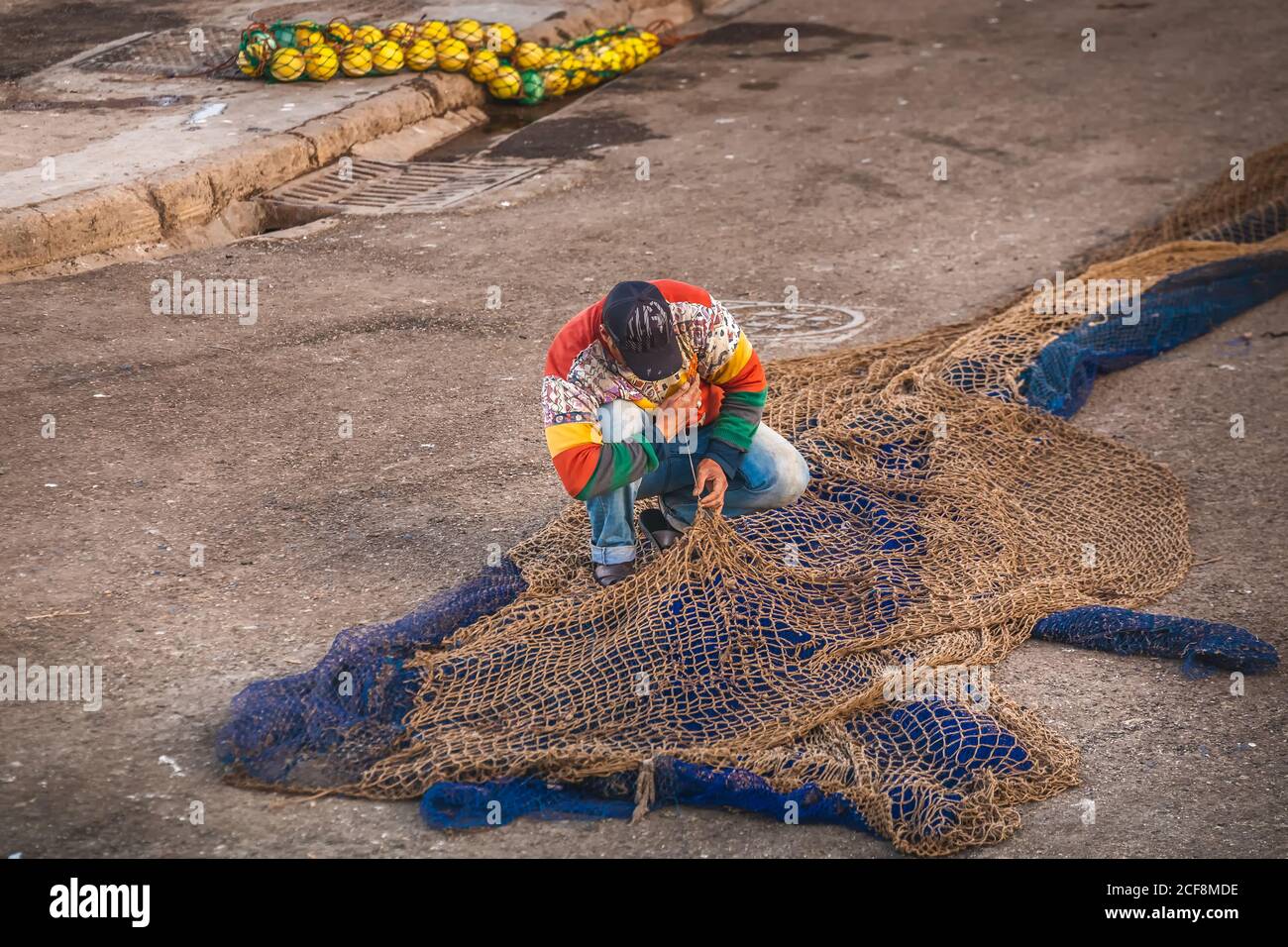 Fisherman fixes the net at the harbour in Essaouira, Morocco. Stock Photo