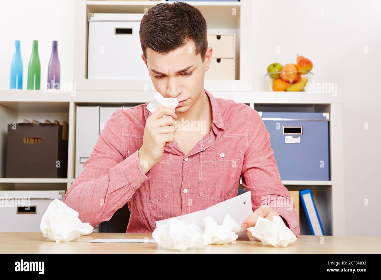 Sad teenage boy cries while reading a letter with handkerchiefs Stock Photo