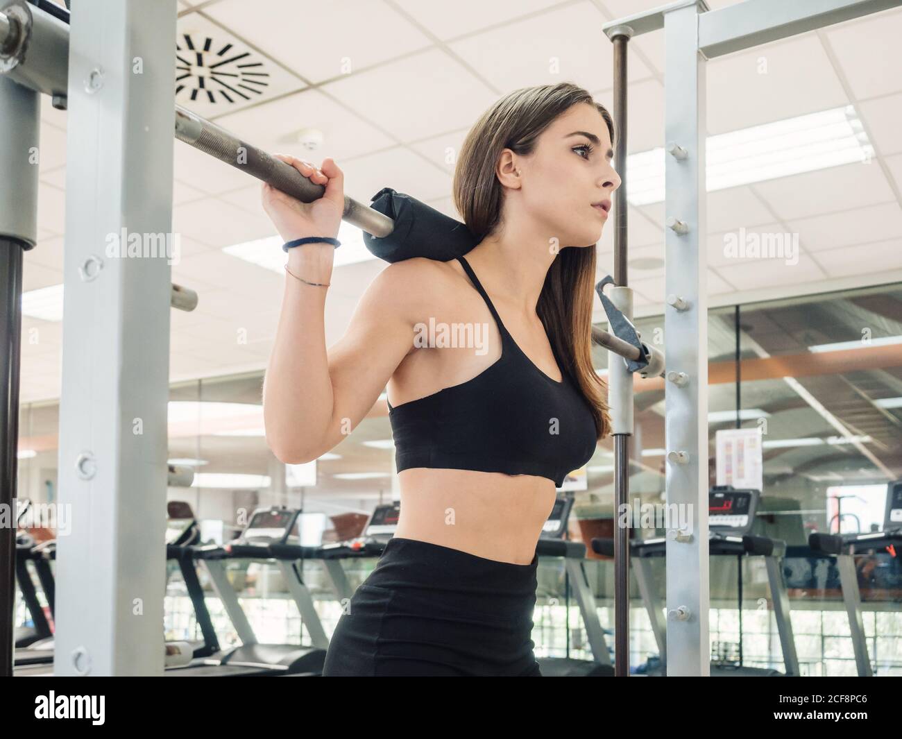 Side view of muscular female in sportswear holding barbell on shoulders and  squatting during workout in gym Stock Photo - Alamy