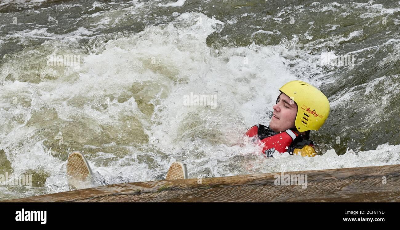 An adolescent boy floats downstream on his back through a stopper at