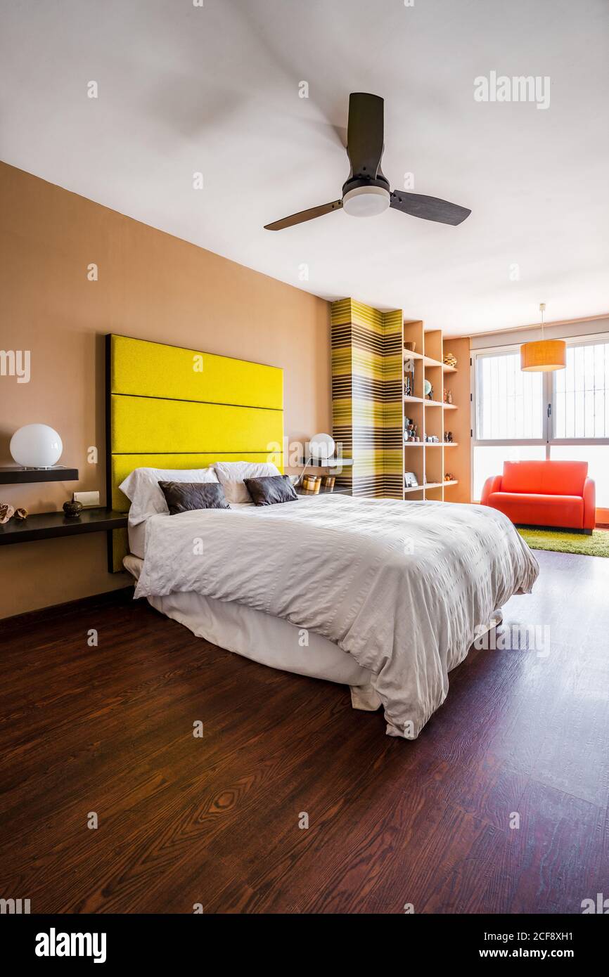 Comfortable bed with bright yellow headboard in modern studio apartment