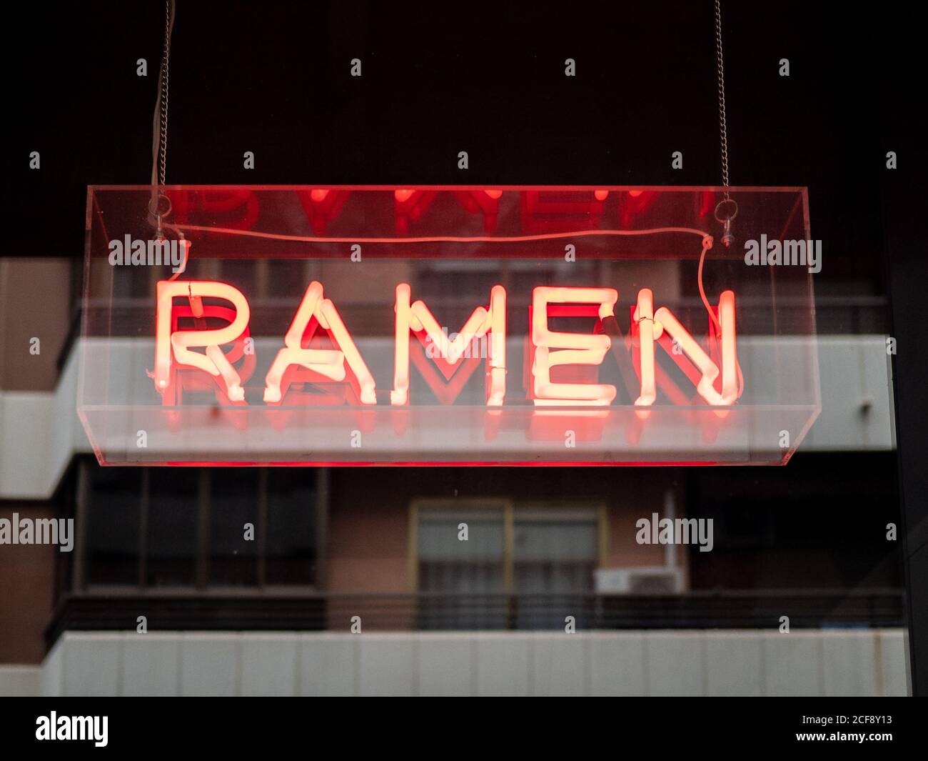 Illuminated signboard with restaurant name Ramen symbolizing traditional Japanese dish hanging outdoors Stock Photo