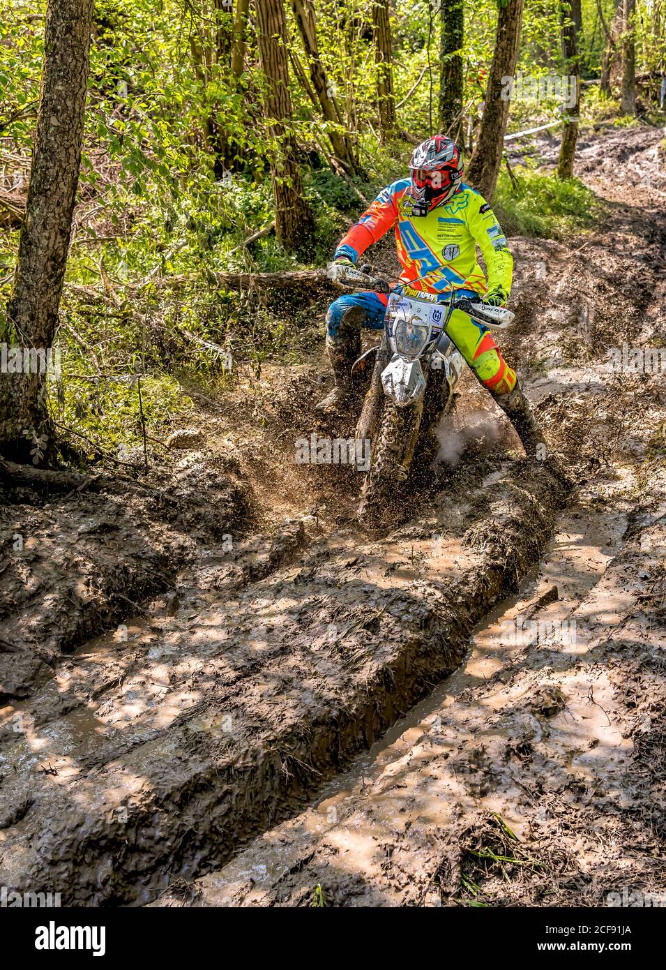 Biandronno, Lombardy, Italy - April 22, 2018: Motocross rider splashing mud on wet and muddy terrain. Open competitions in motocross. Stock Photo