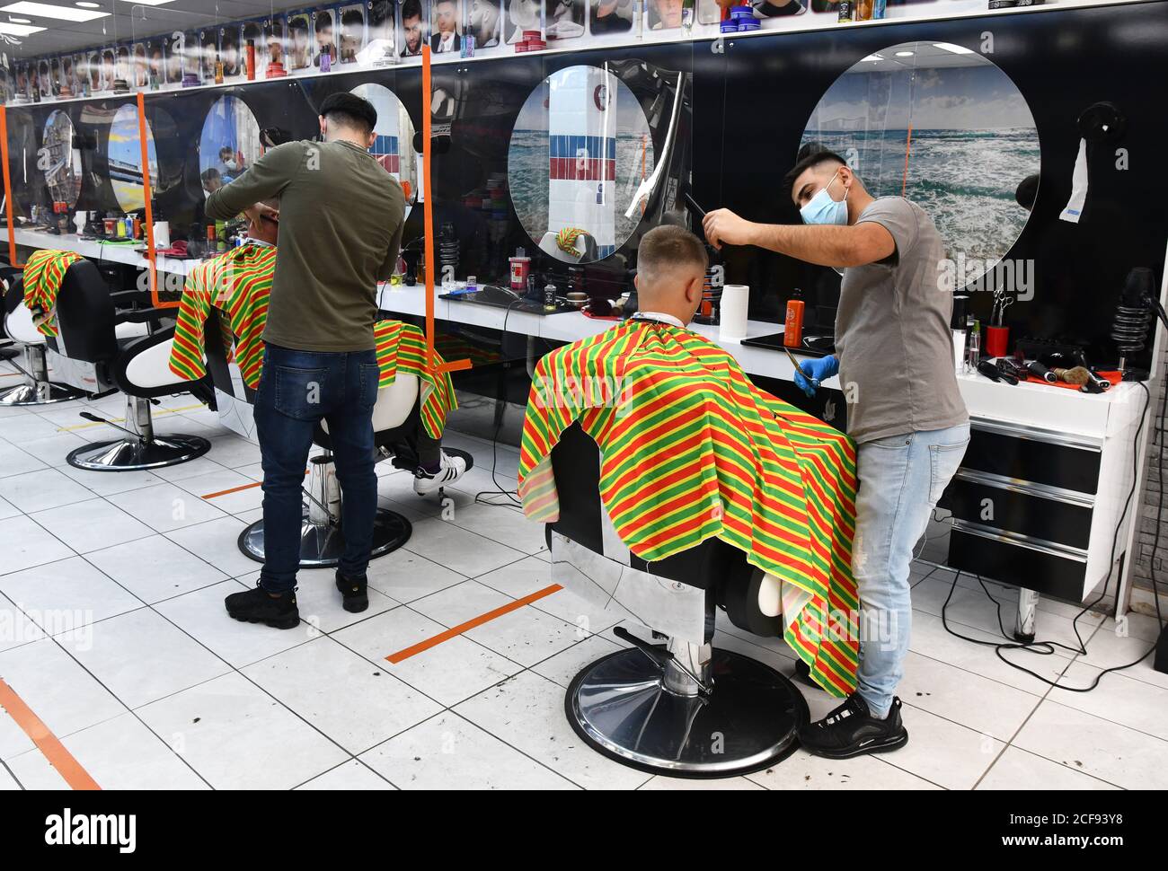 Barbers at work wearing face masks in unisex barber shop salon in Shrewsbury, Britain, Uk during the Covid 19 pandemic Stock Photo