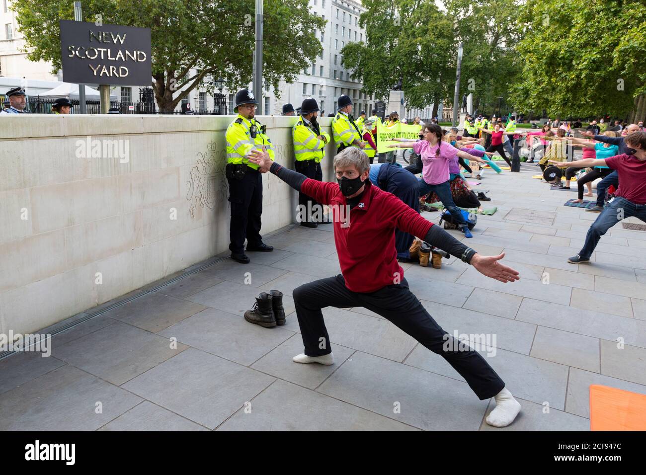Protesters strike yoga poses outside New Scotland Yard during Extinction Rebellion demonstration, Westminster, London, 1 September 2020 Stock Photo