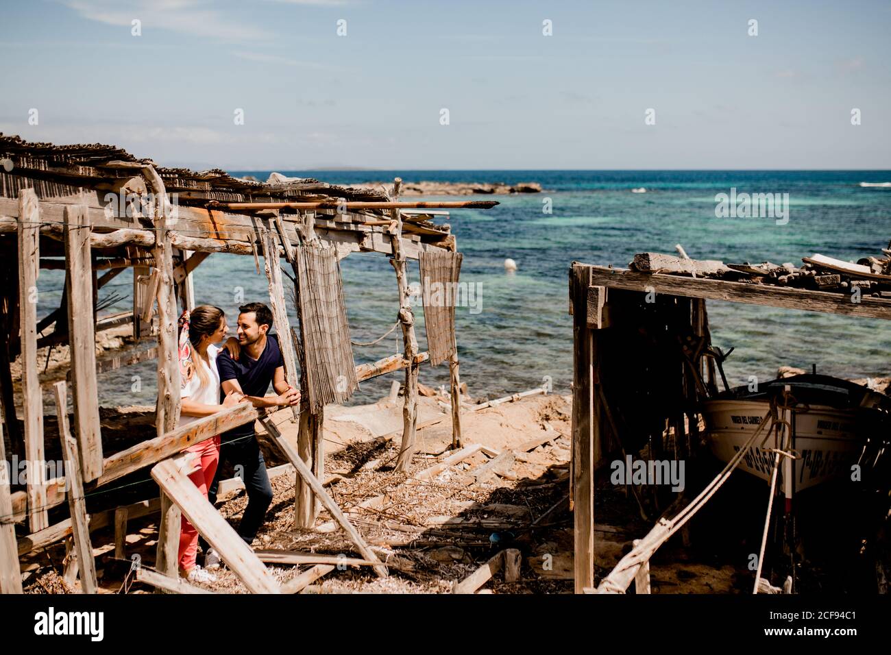 Enamored man and Woman hugging on shore under shabby wooden canopy in summer and looking at each other Stock Photo