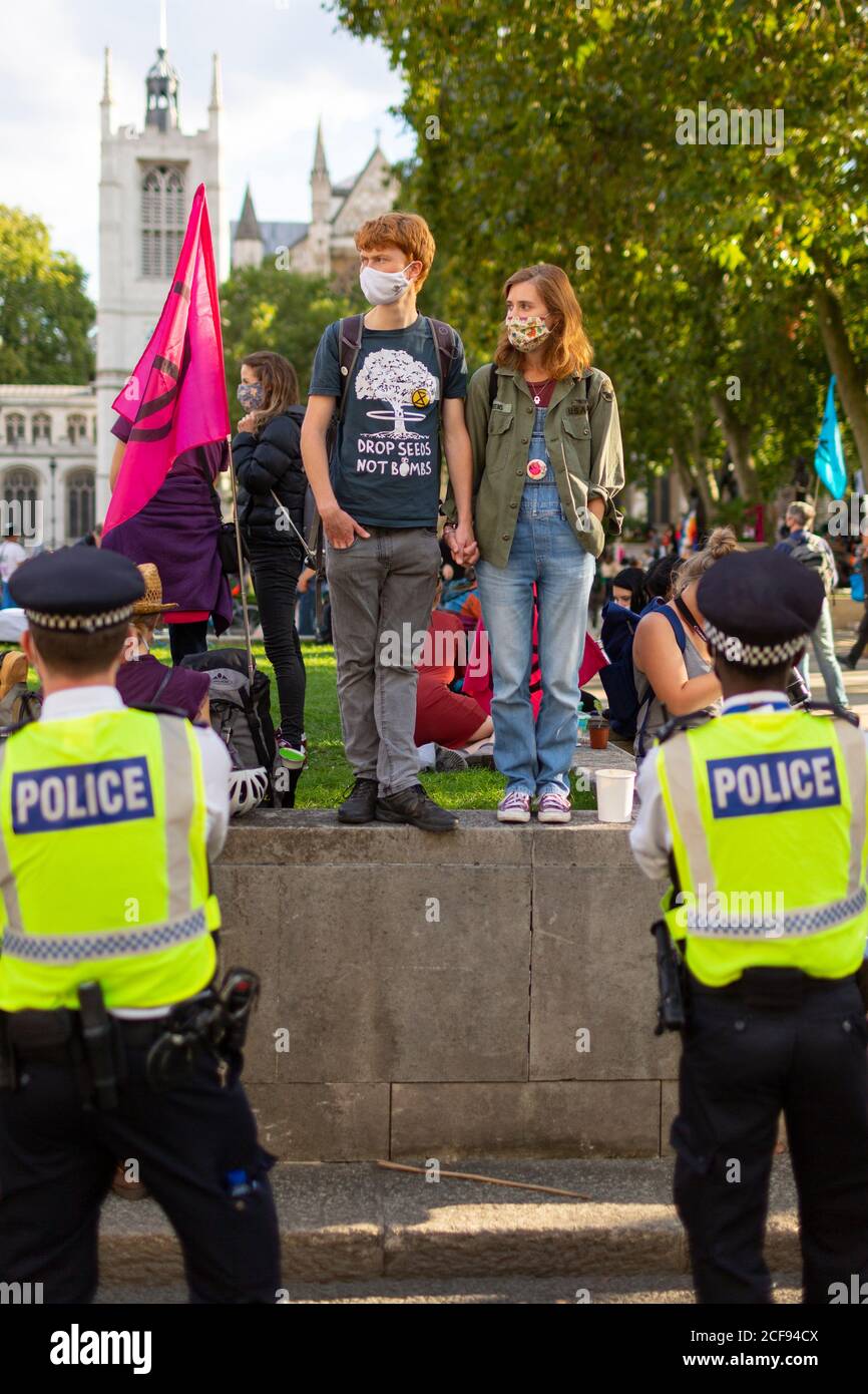 Young protesters holding hands in front of police during Extinction Rebellion demonstration, Parliament Square, London, 1 September 2020 Stock Photo