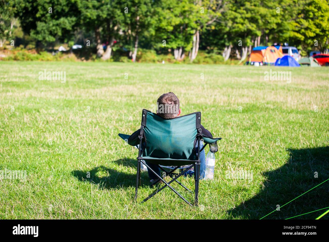 Man chilling in camping chair alone at We Are Not a Festival socially distanced event in Pippingford Park - camping with a festival vibe Stock Photo