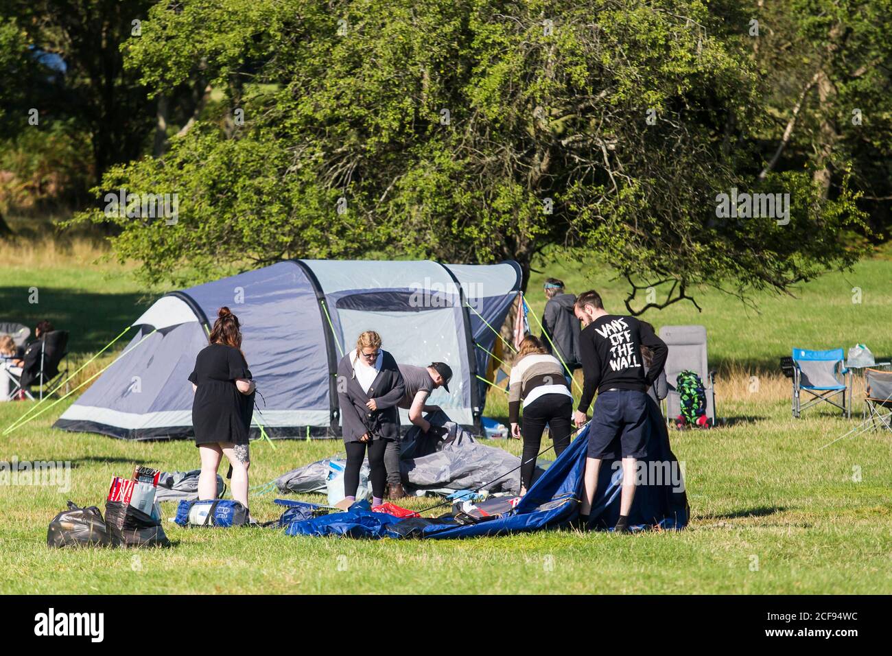 Group of friends taking down their tent at We Are Not a Festival socially distanced event in Pippingford Park - camping with a festival vibe Stock Photo
