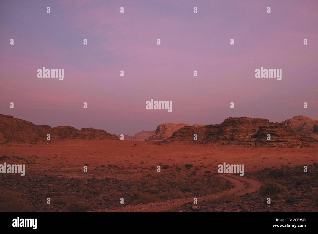 Violet cloudy sky over rough mountain ridge and Wadi Rum desert in evening in Jordan Stock Photo