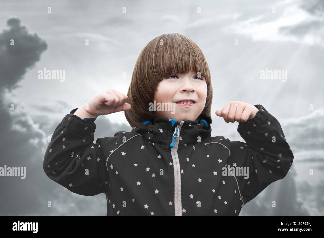 Boy is showing power sign at cloudy background Stock Photo